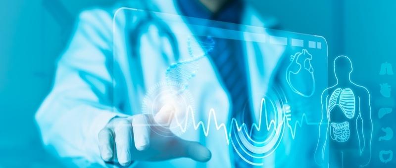 Medizinisches Fachpersonal in weißem Kittel berührt eine digitale Schnittstelle, die den Herzrhythmus und die menschliche Anatomie in Blautönen zeigt.