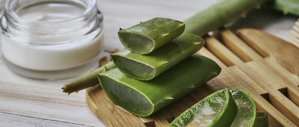 Aloe-Vera-Scheiben und Feuchtigkeitscreme auf einem Holztisch.