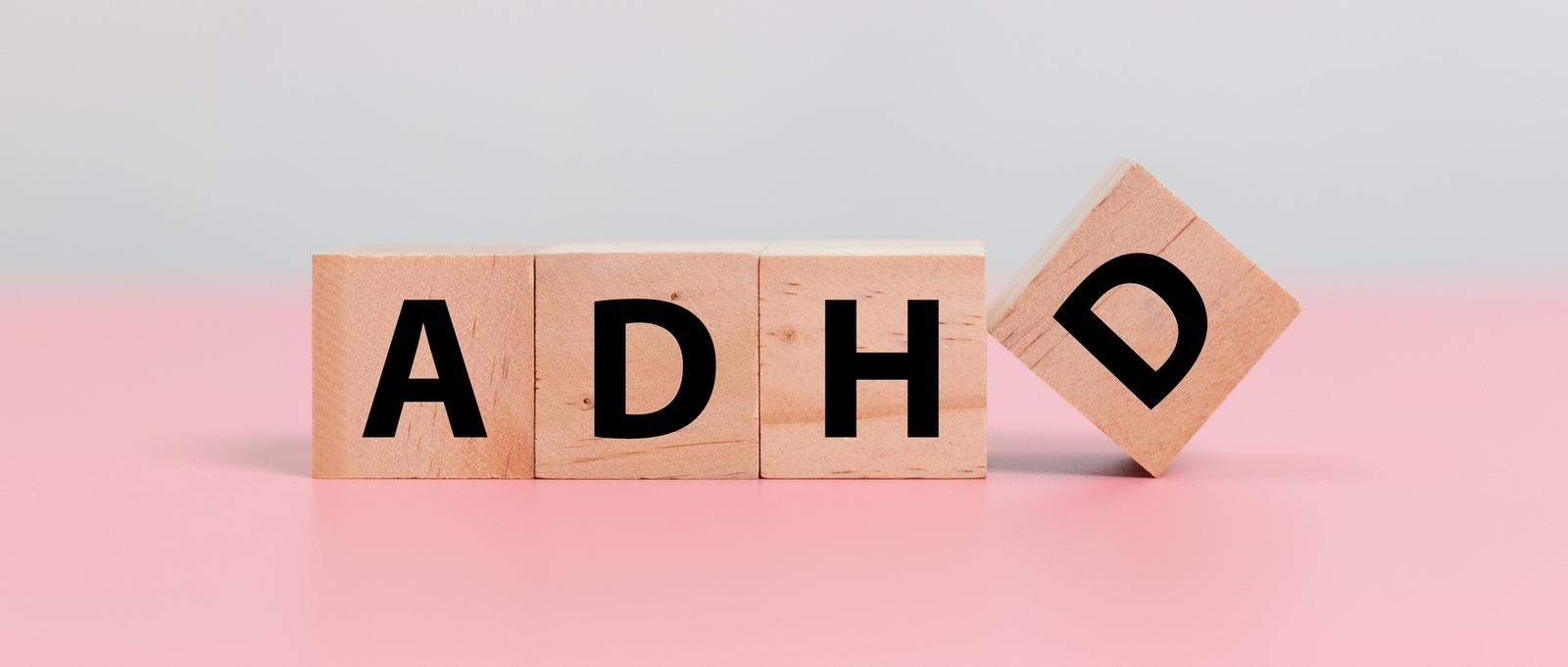 Wood cube block Abbreviation of ADHD on pink table. Attention Deficit Hyperactivity Disorder.