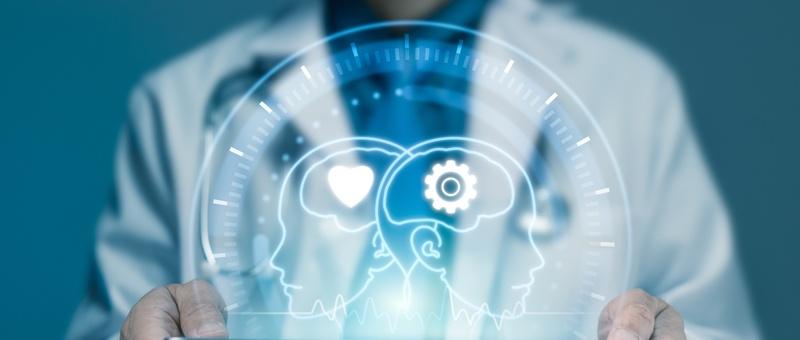 Medizinisches Fachpersonal hält ein digitales Hologramm, das zwei Profilköpfe mit Herz- und Zahnradsymbolen zeigt, die für die Gesundheitstechnologie stehen.