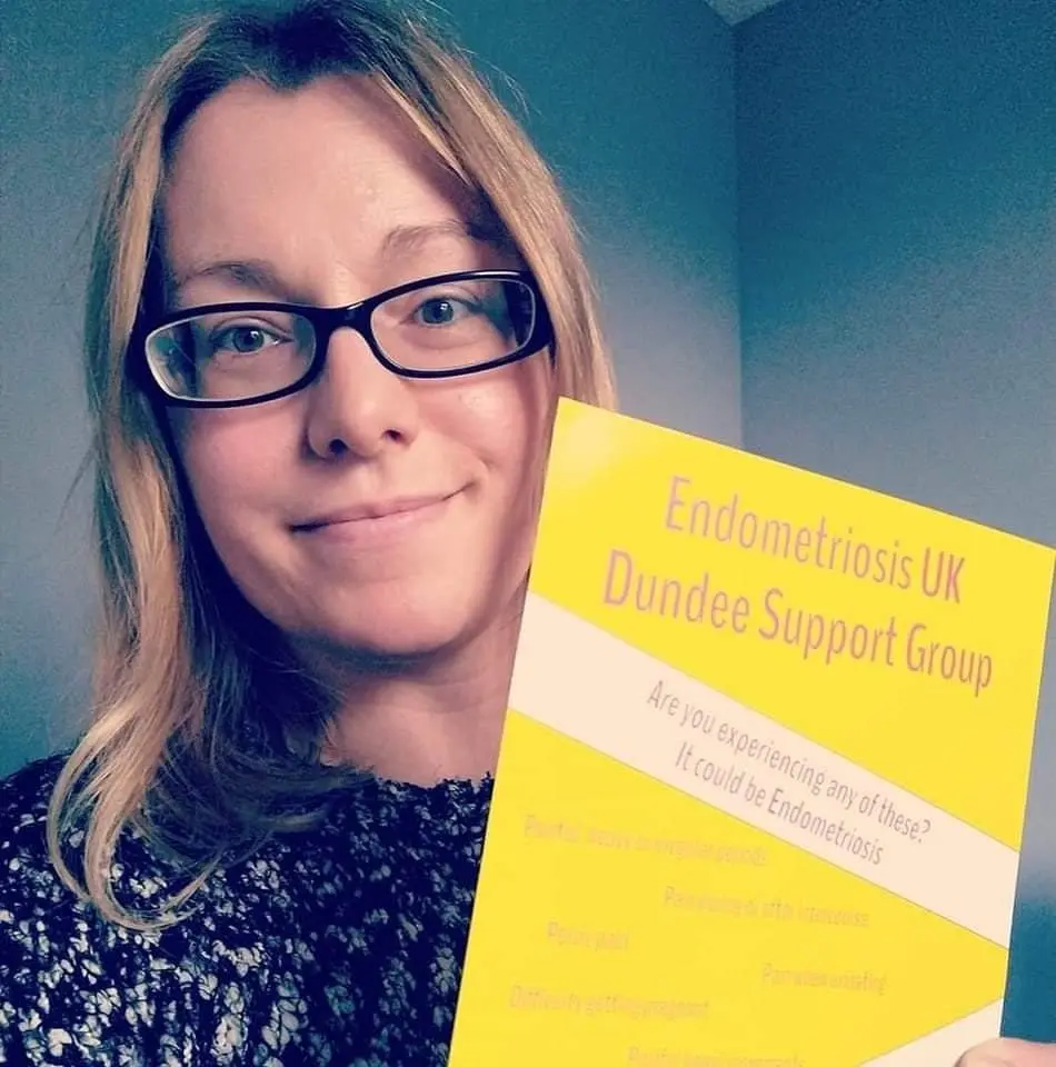 Foto von Vicky, die ein Poster der "Endometriosis UK Dundee Support Group" hochhält
