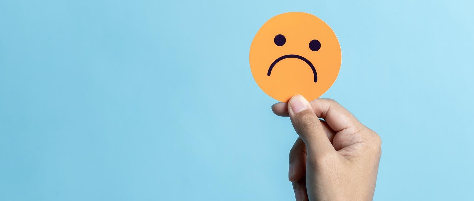 Ein orangefarbener Kreis mit einem traurigen Gesicht auf einem blauen Hintergrund.