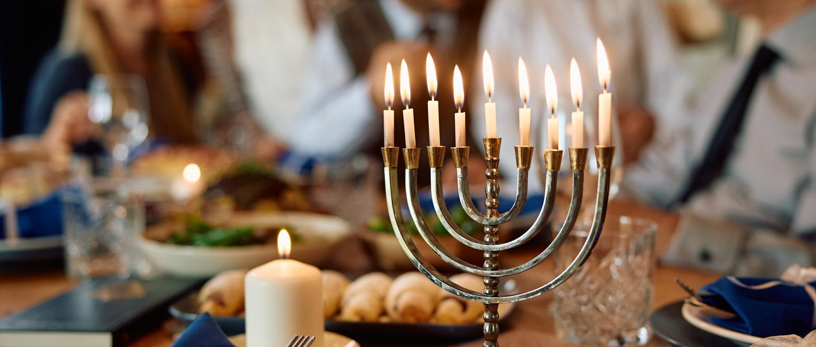 Beleuchtete Menora mit jüdischer Großfamilie im Hintergrund an Chanukka.
