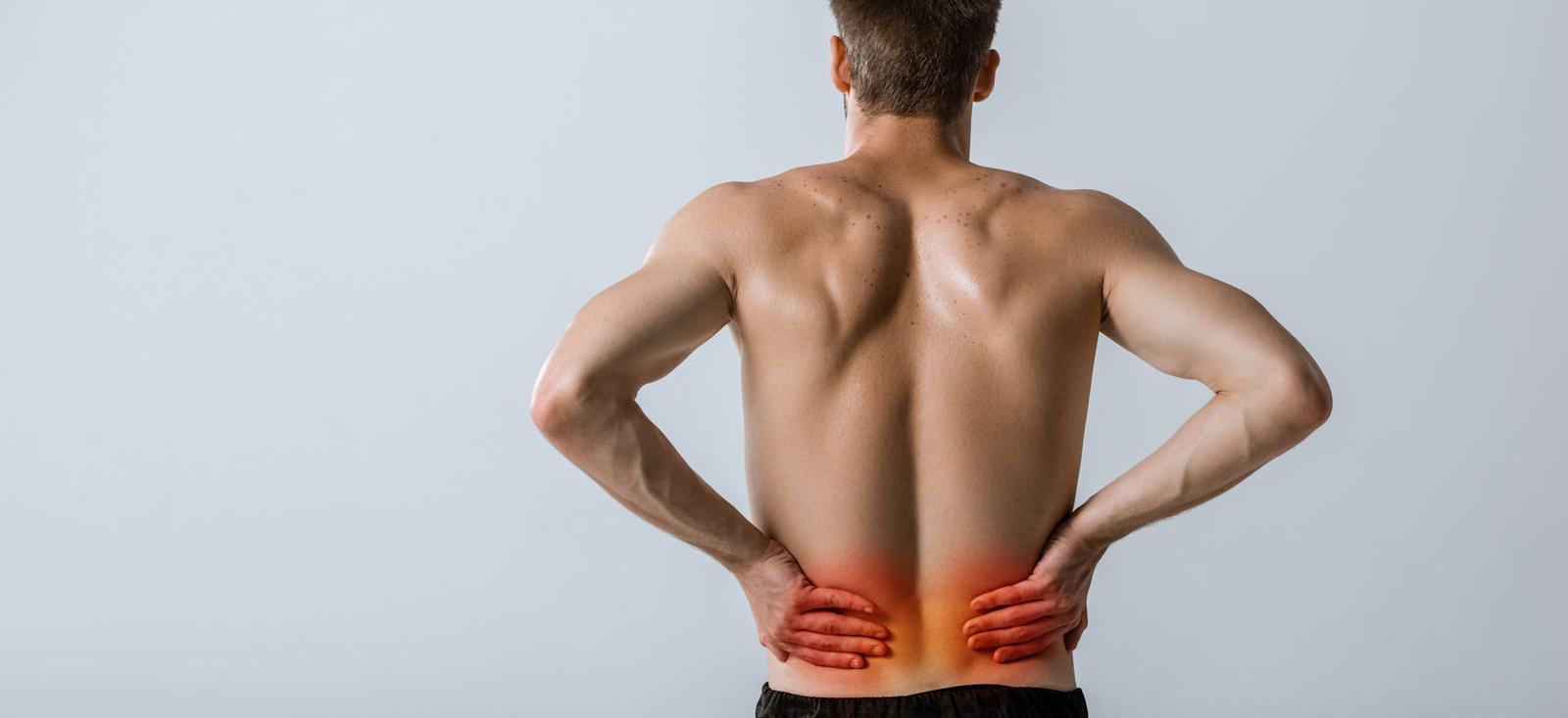 Ein Mann hält sich den unteren Rücken.