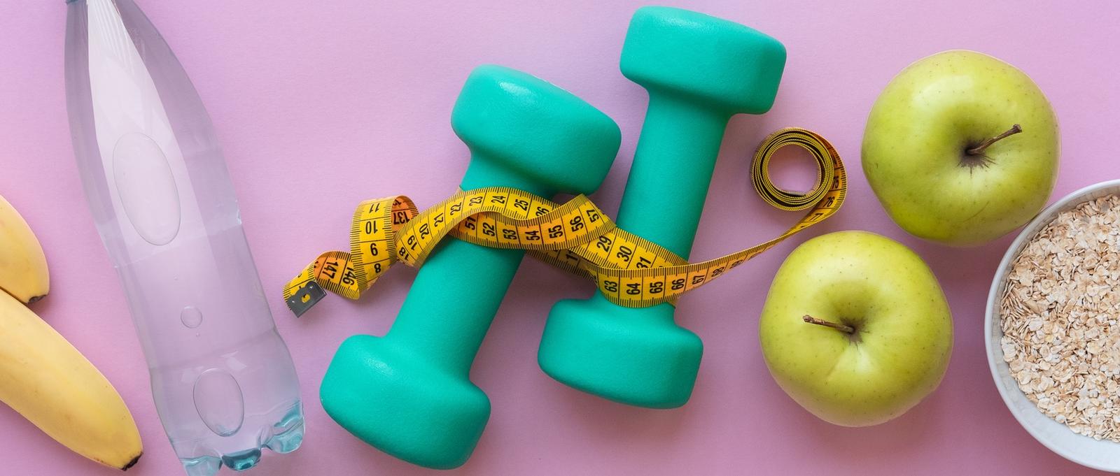 Fitness-Konzept - Äpfel, Wasser, Hanteln und Springseil auf rosa Hintergrund