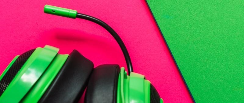 Gaming-Headset mit Mikrofon vor rosa und grünem Hintergrund.