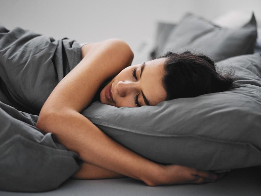 Frau schläft in grauem Bett