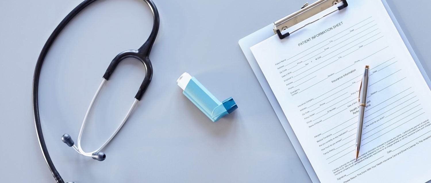Stethoskop, blaues Inhaliergerät und Patienteninformationsformular mit Stift auf hellblauem Untergrund, das die medizinische Versorgung darstellt.
