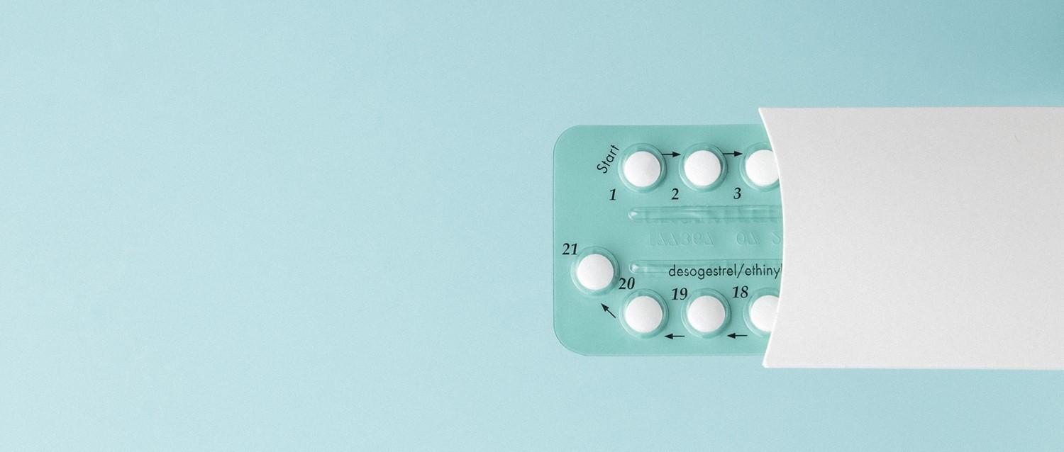 Antibabypillen-Packung mit nummerierten weißen Tabletten in einer blaugrünen Blisterpackung vor einem hellblauen Hintergrund.
